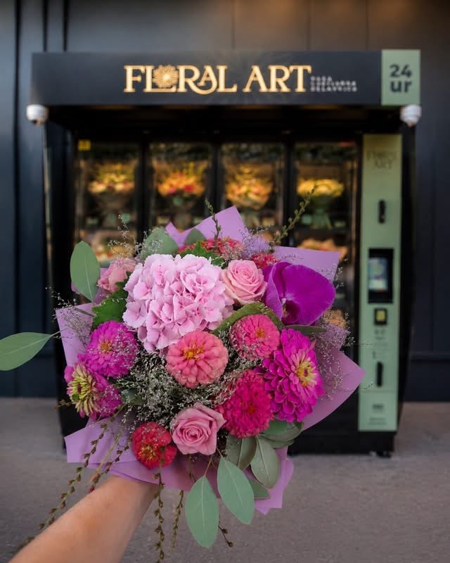 Avtomat FloralArt in roka, ki drži zavit vijolično-rožnat šopek